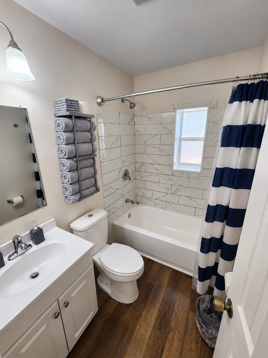 Columbia main bathroom with neatly rolled gray towels, white vanity, tiled bathtub and closed toilet lid