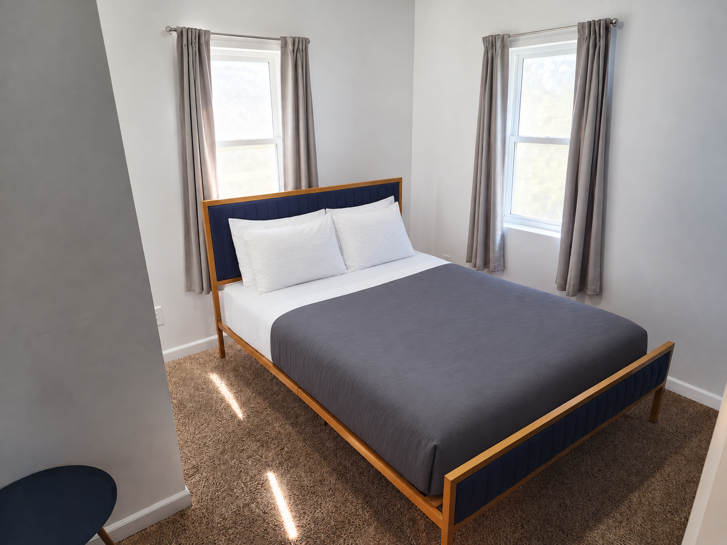 Columbia bedroom with navy and gold bed, gray comforter and neatly opened gray curtains