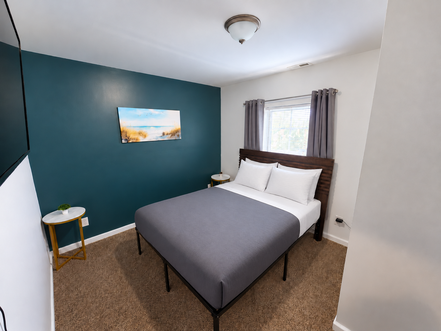 Columbia bedroom with teal accent wall, beach artwork, gray comforter, two open curtain panels and ceiling light off