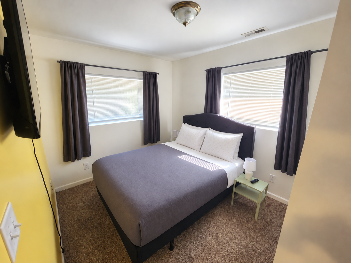 Columbia bedroom with upholstered bed, gray comforter and neatly opened dark curtains