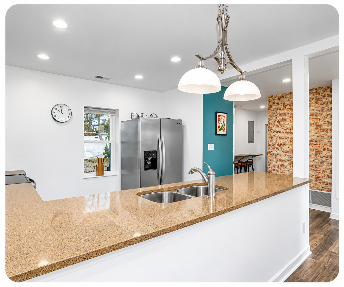 Columbia Urban Oasis furnished kitchen with tan island, pendant lights, stainless-steel appliances and exposed brick