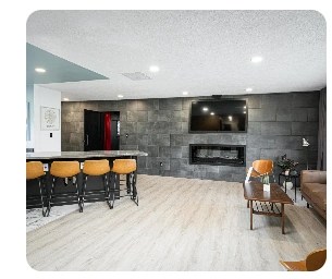 Furnished living room with large wall-mounted TV, modern fireplace, comfortable seating and kitchen island