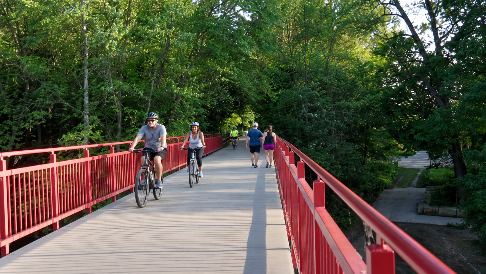 Cyclists and walkers enjoying the red Monon Trail bridge in Indianapolis in summer